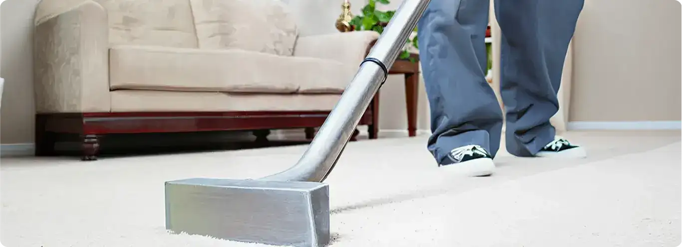 Carpet cleaning technician using a hot-water extraction wand on a light-colored carpet in a living room, Richmond, VA.