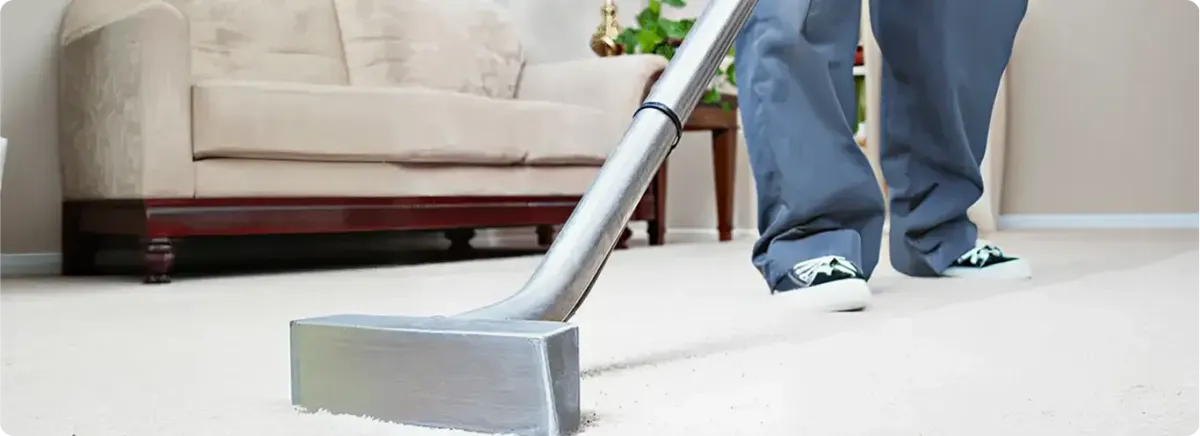 Carpet cleaning technician using a hot-water extraction wand on a light-colored carpet in a living room, Richmond, VA.